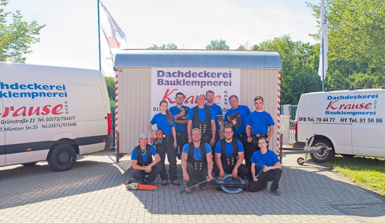 Das Team der Dachdeckerei Krause vor den Firmenfahrzeugen
